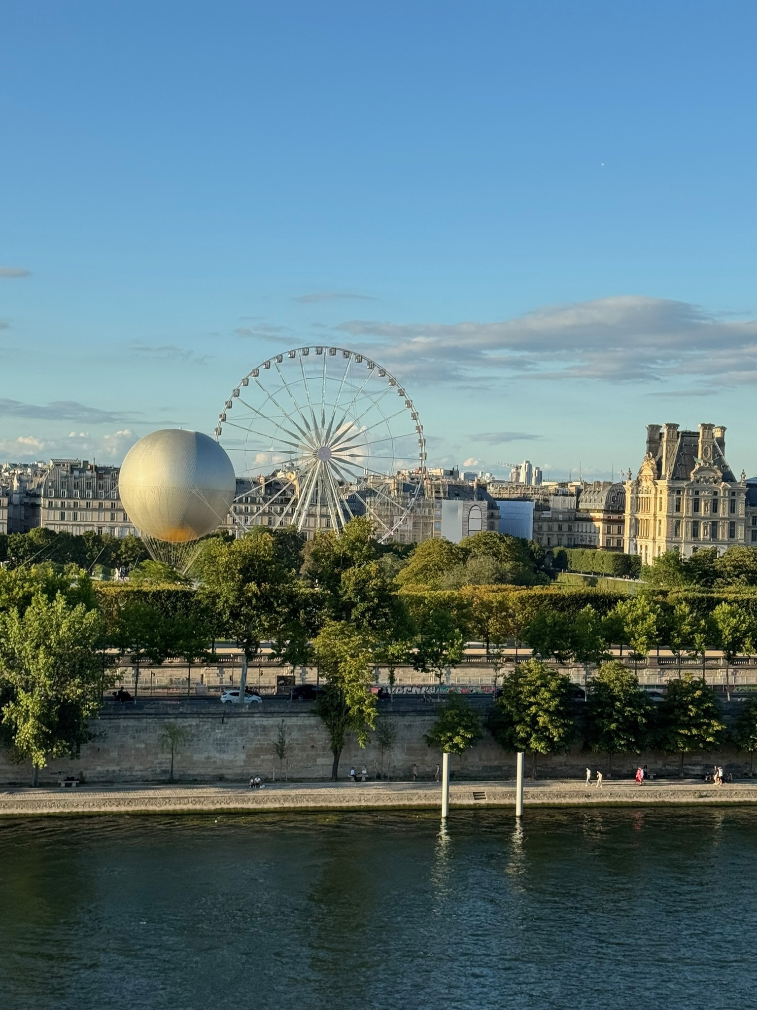 panoramic view of Paris in summer from the Musée d'Orsay rooftop with the Seine and Ferris wheel.