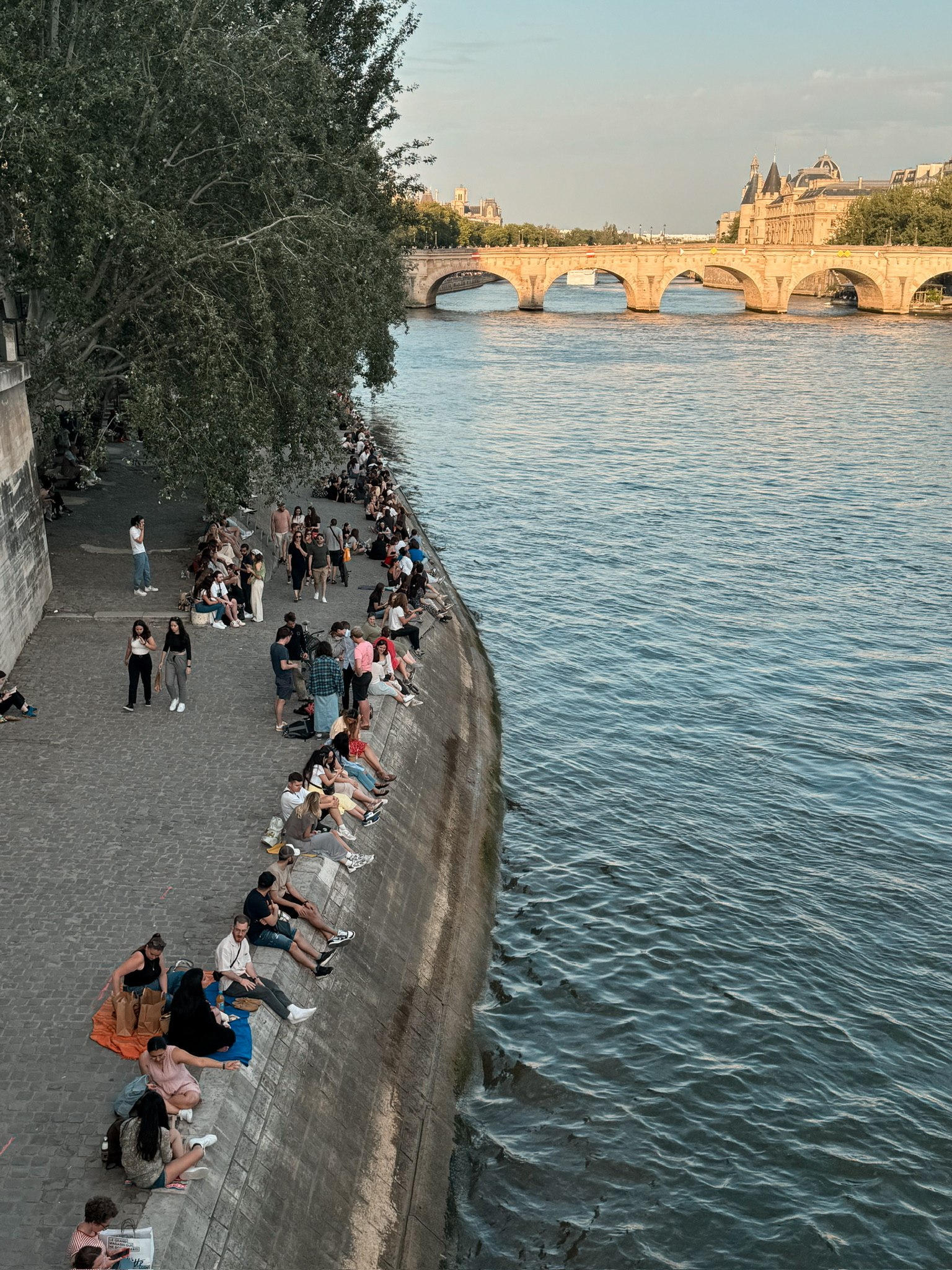 locals sitting along the Seine River banks in Paris on a summer evening