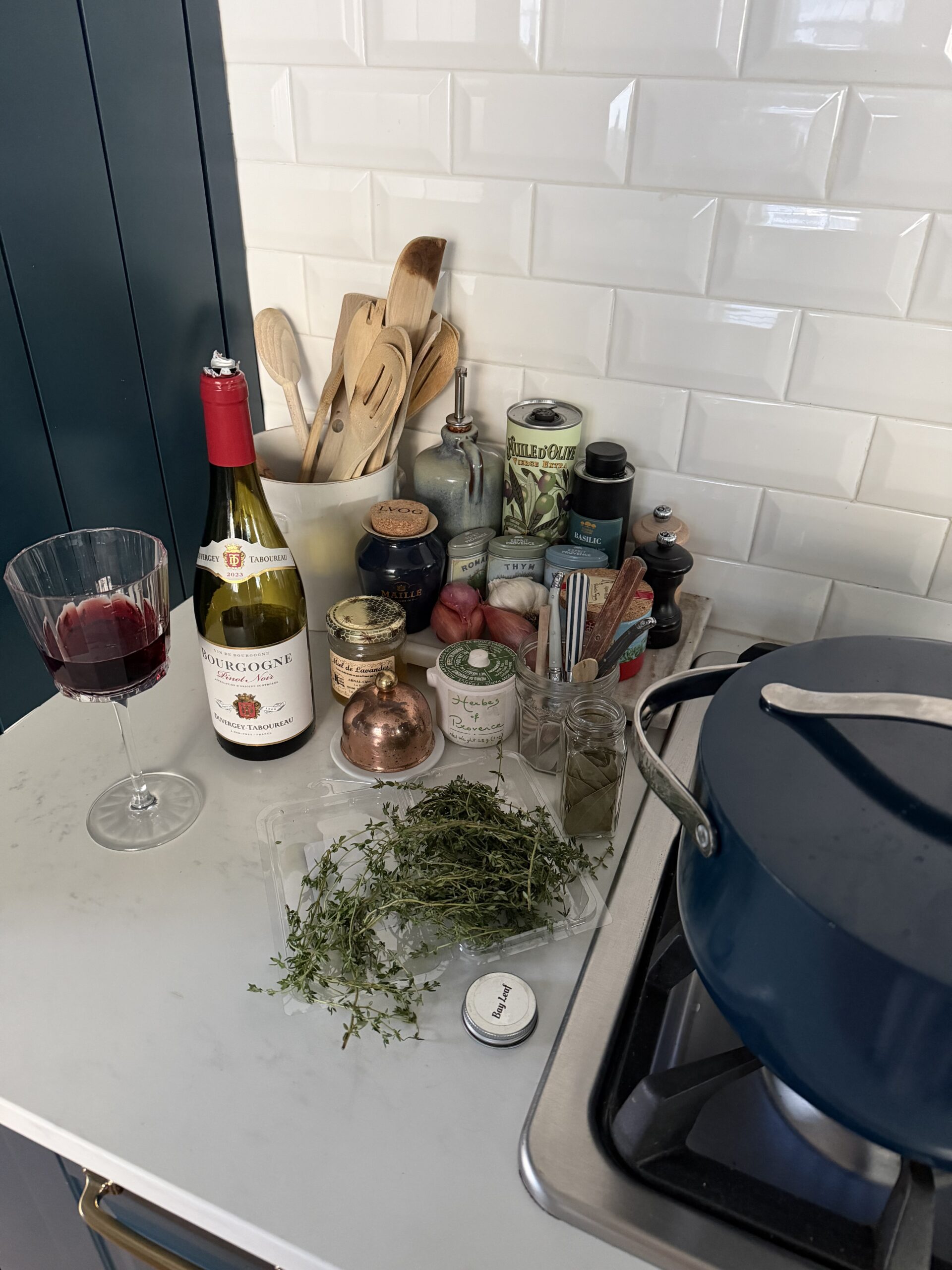 Navy pot on stove with bottle of wine and spices on a fall evening.